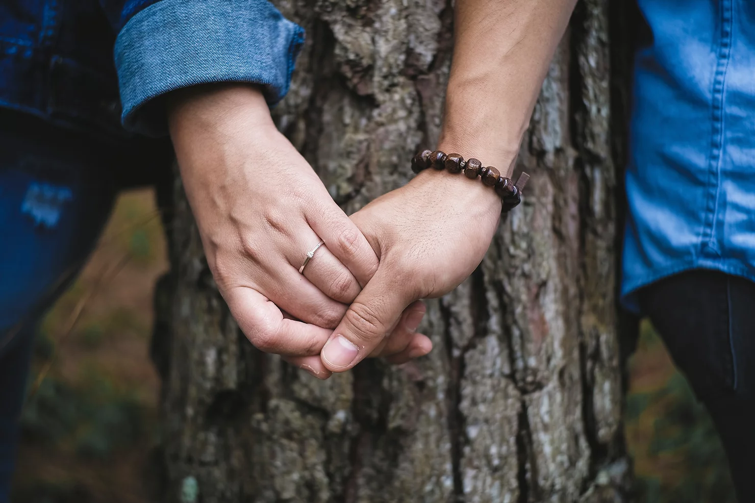 Auf dem Bild sieht man zwei Hände die sich halten. Eine Person trägt einen Ring. Im Hintergrund steht ein Baumstamm. Das Bild steht für den Blogbeitrag: Lust auf einen Neustart?