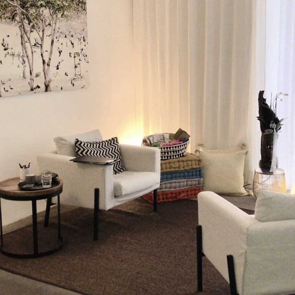 Praxisraum in Chur. Beige Sessel und brauner Teppich. Gemütlicher Raum mit warmem Licht. Der Stil ist modern.