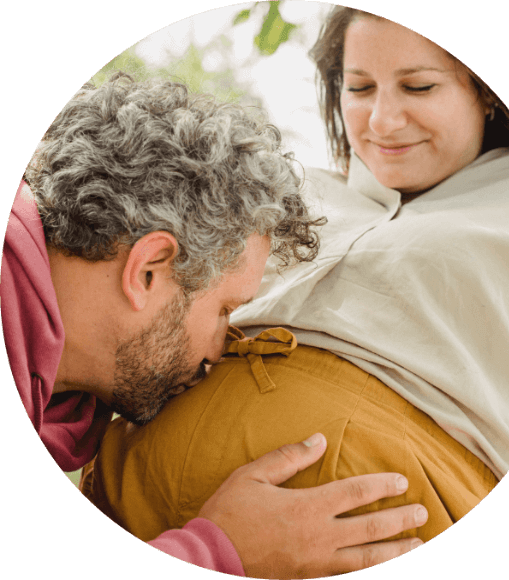 Ein Mann küsst seiner schwangeren Frau den Bauch. Dieses Bild steht für das Paartherapie -und Paarcoaching - Angebot für Paare mit Kinderwunsch und während der Schwangerschaft.